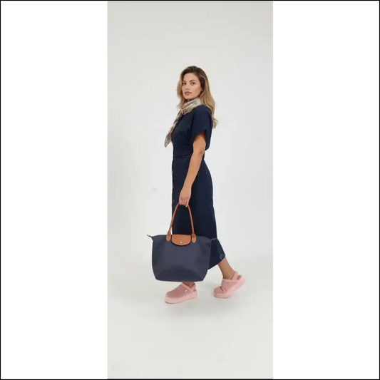 Model showcasing Large Longchamp Tote in navy blue, paired with a stylish outfit and pink shoes.
