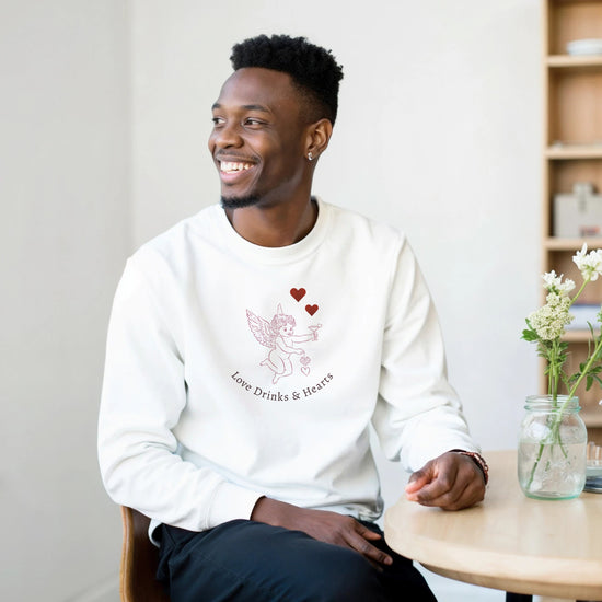 Love Sweatshirt worn by a smiling man, featuring a cute graphic of a winged character with hearts.