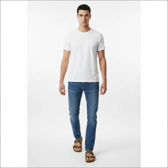 Man wearing Birkenstock Mayari sandals in stone with a white t-shirt and blue jeans.