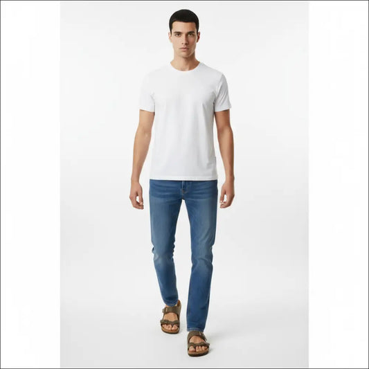 Man wearing Birkenstock Mayari sandals in stone with a white t-shirt and blue jeans.