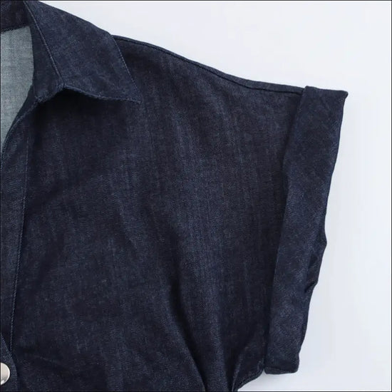 Elegant denim fabric detail of the sleeve from a Skjortklänning, showcasing stylish buttoned design.