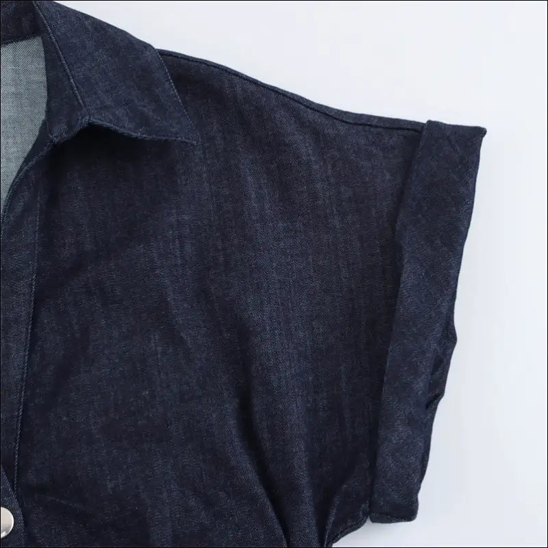 Elegant denim fabric detail of the sleeve from a Skjortklänning, showcasing stylish buttoned design.